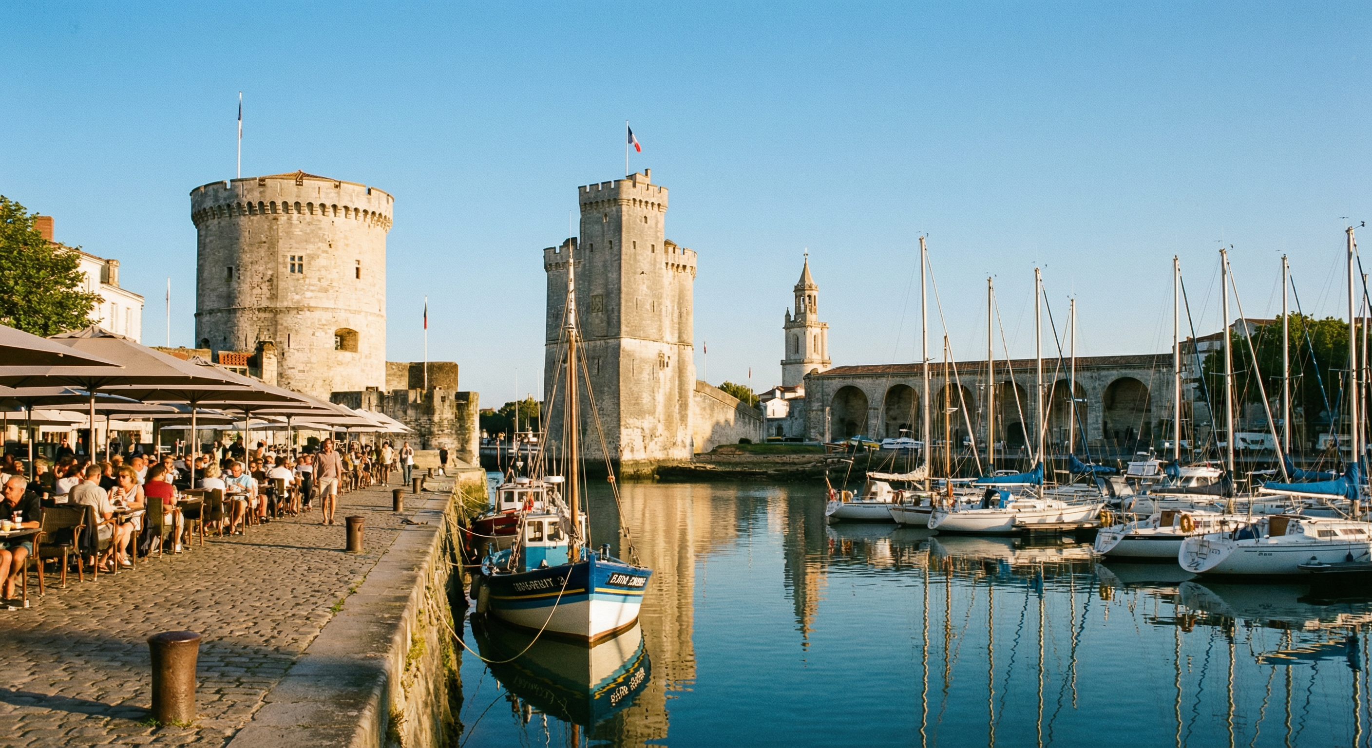 Vieux-Port de La Rochelle avec les tours médiévales, terrasses de restaurants le long du quai, bateaux amarrés