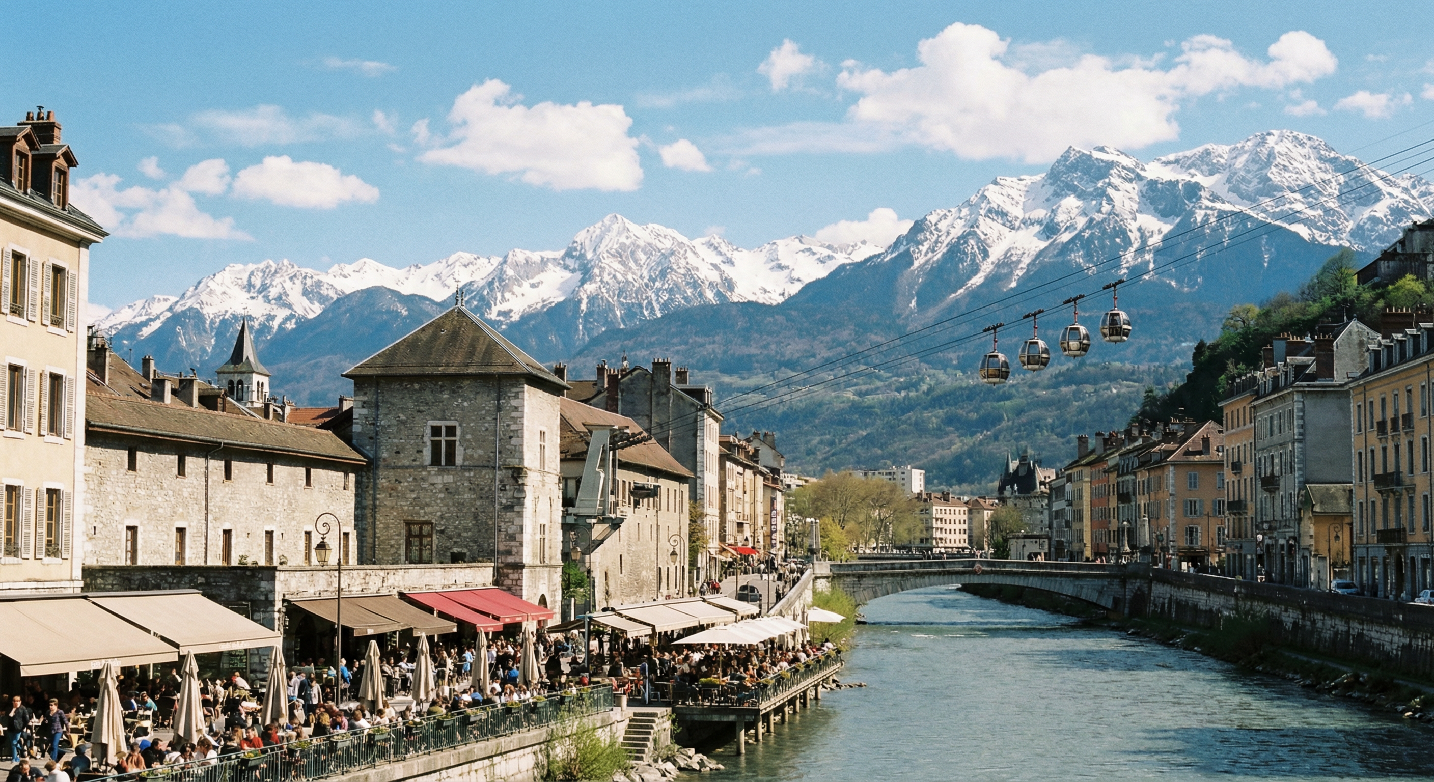 Vue de Grenoble avec les Alpes enneigées, quais avec terrasses de cafés et restaurants, téléphérique de la Bastille