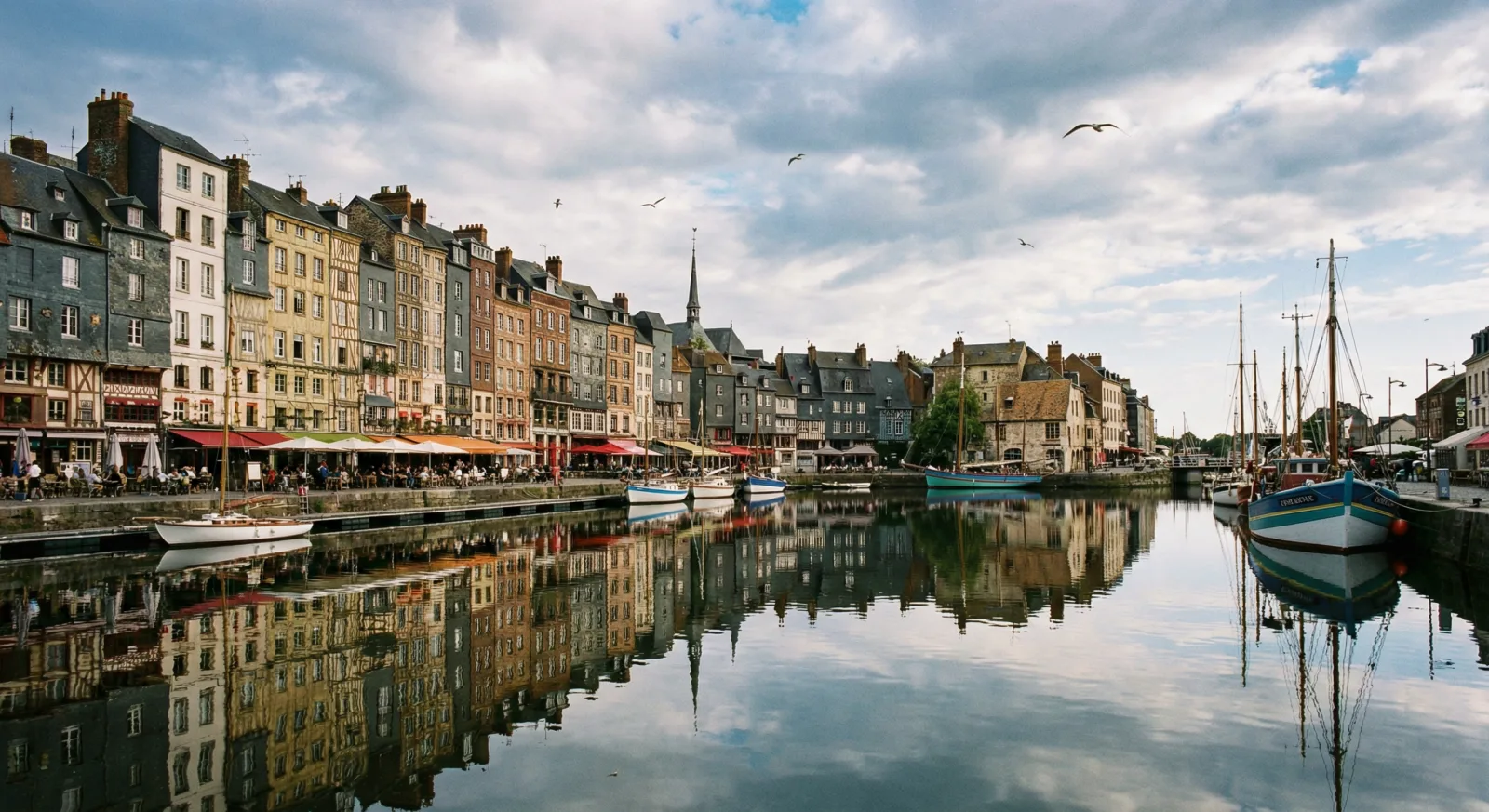 Port de Honfleur dans le Calvados : maisons à colombages, terrasses de restaurants, bateaux de pêche
